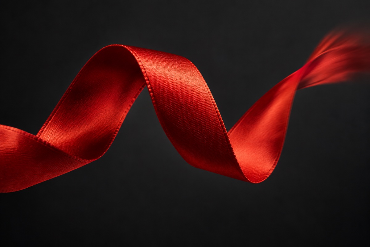 Vermilion silk ribbon twisting through a dark studio with a softly blurred trailing edge